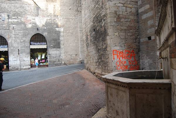 Stone fountain with graffiti, medieval alleys and shops, Perugia