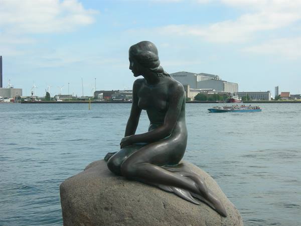 The Little Mermaid statue in Copenhagen on a rock facing the harbor