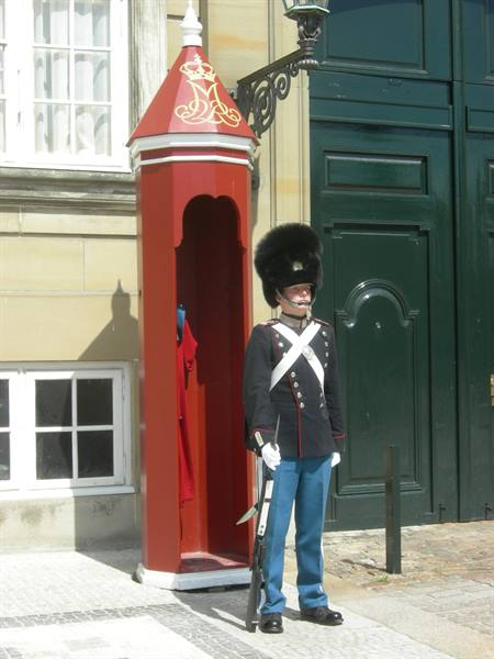 Danish royal guard in black bearskin standing beside the red sentry box, Amalienborg
