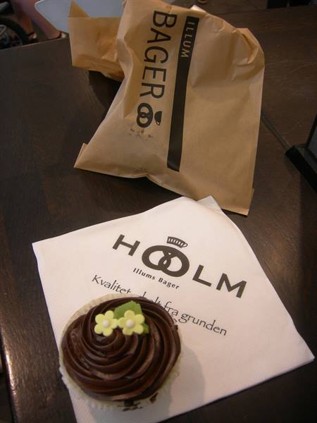 Chocolate cupcake on Holm napkin next to a brown Illums Bager paper bag