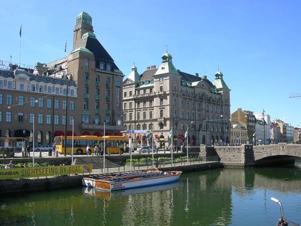 Historic buildings with green roofs along the canal, yellow buses and tour boat