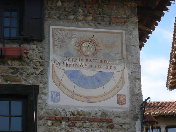 Painted sundial with sun and French motto on stone wall