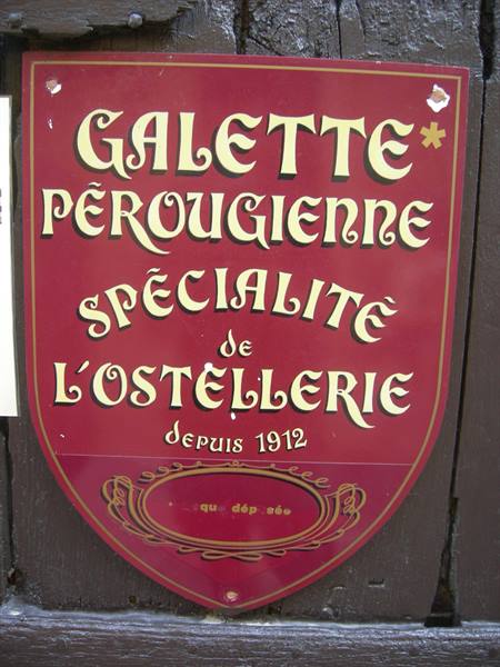 Red shield-shaped sign reading Galette Pérougienne, inn specialty since 1912