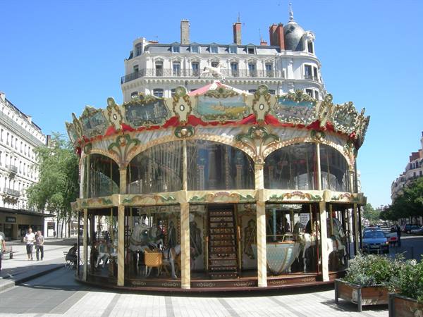Antique golden wooden carousel on a sunny square, behind Haussmann buildings