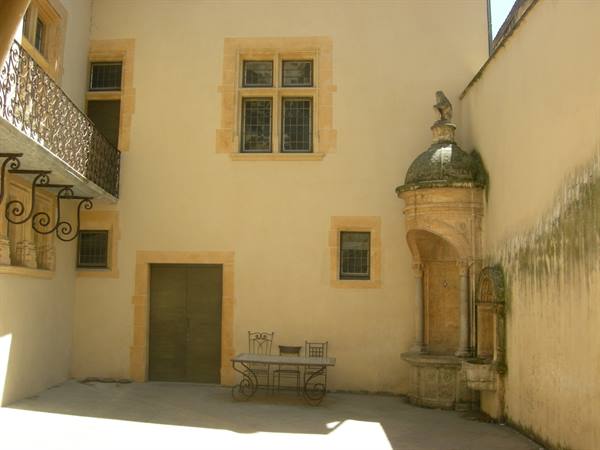 Stone courtyard with wrought iron balcony and baroque fountain, bright sunlight