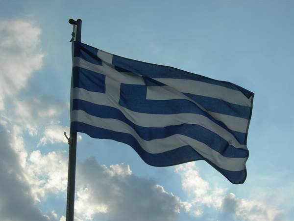 Greek blue and white striped flag waving on a pole against clouds
