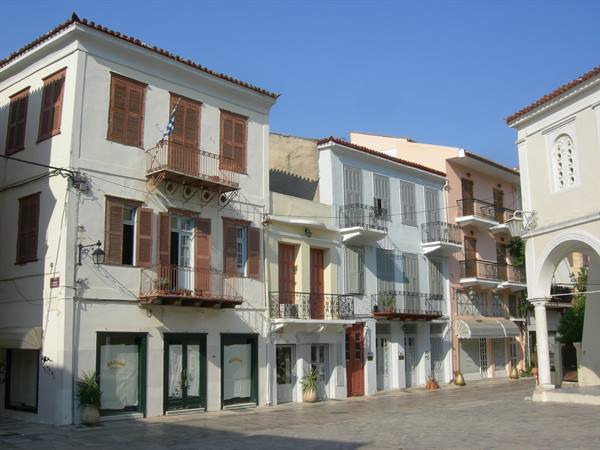 Neoclassical houses with wooden shutters and balconies facing a paved square