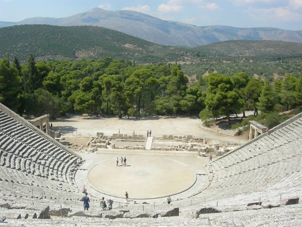 Ancient theater of Epidaurus, stone tiers, circular orchestra, visitors and green pine trees