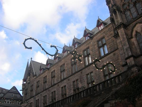 Gothic stone town hall with festive lights strung against a cloudy sky