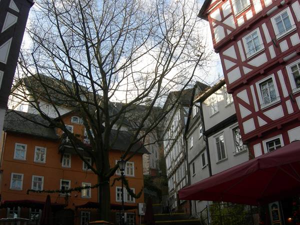 Red and orange half-timbered houses, bare tree, market square umbrella, winter light