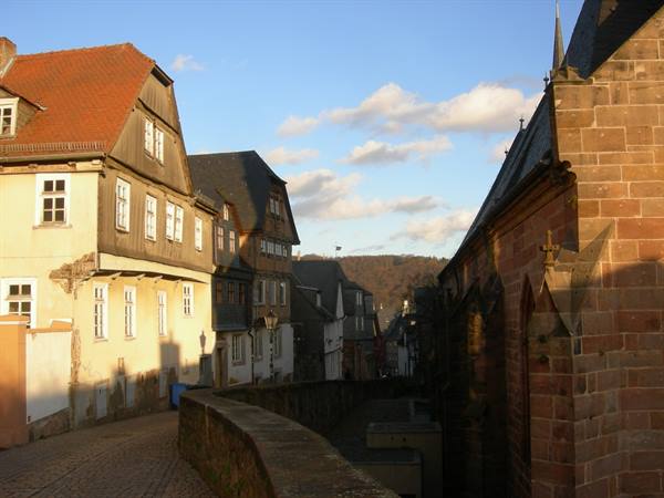 half-timbered houses beside a red sandstone church, cobbled narrow street