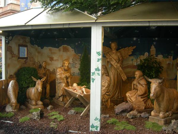 Carved wooden nativity scene with baby Jesus, angel, ox and donkey under gazebos