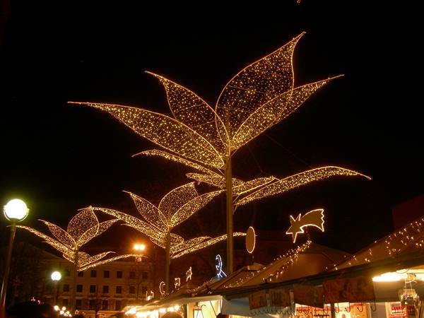 Golden leaf-shaped lights glowing above the Christmas market stalls at night