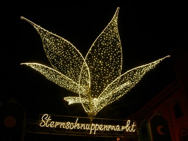 Star-shaped light sculpture above the Sternschnuppenmarkt sign in Wiesbaden at night