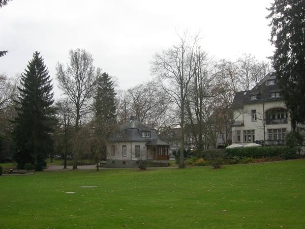 Lawn in front of a historic villa and a stone house with grey roof