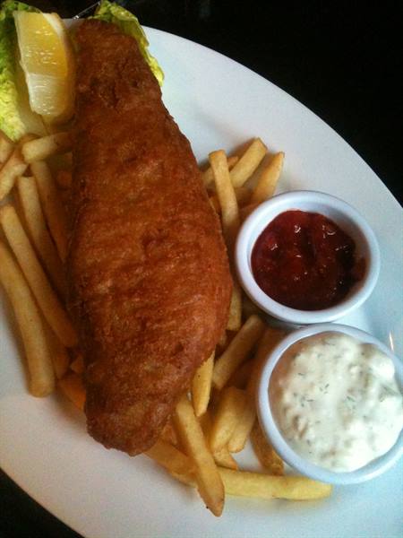 Battered fish and chips with tartar sauce and a lemon wedge