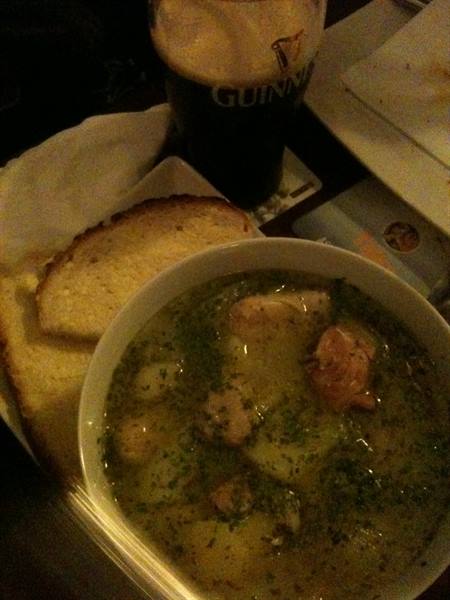 Fish soup in white bowl with bread and a pint of Guinness
