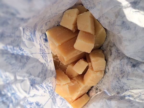 Cubes of aged cheese wrapped in patterned paper, lit by sunlight