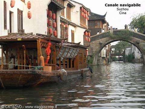 Wooden boat on Suzhou canal with red lanterns and arched bridge