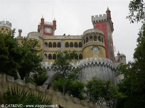 Pena Palace in Sintra, red and yellow towers rising above trees under grey sky