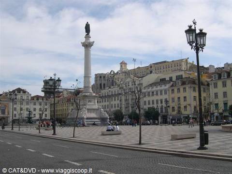 Column with statue in the middle of Praça do Rossio, Lisbon, among colorful buildings