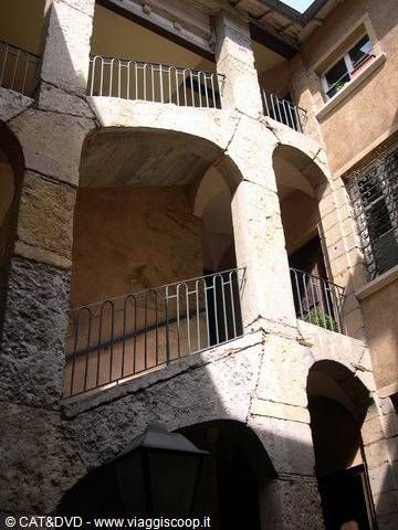 Medieval stone courtyard with double arched staircase and iron railings