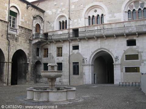 Stone fountain in a courtyard with arches and historic buildings, daylight