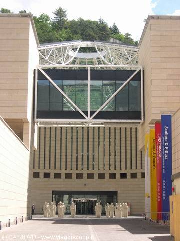 Stone facade with white steel truss and statues at the entrance, Chiasso