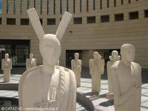 Limestone stylized figure sculptures in front of a modern building