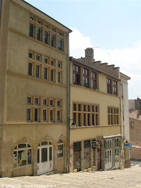 Ochre buildings with tall mullioned windows along a steep cobbled climb