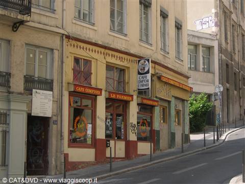 CAFÉ CENTRALE facade with red signage and graffiti on a sloping street