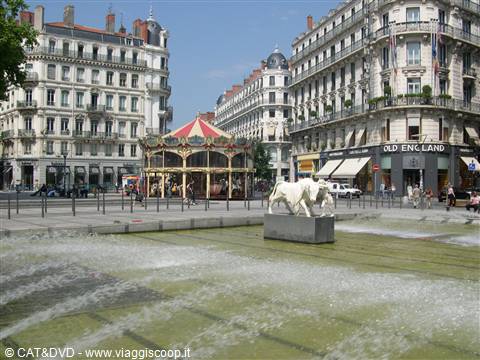 Fountain with horse sculptures and old carousel among Haussmann buildings, Lyon