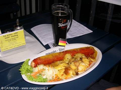 Currywurst with potatoes and salad, dark Köstritz beer on blue table