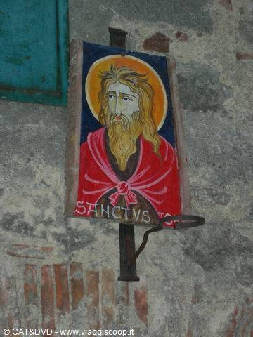 Painted panel of a bearded saint on an old stone wall