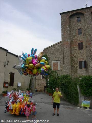 Man and children with bunch of colorful balloons among medieval stone houses