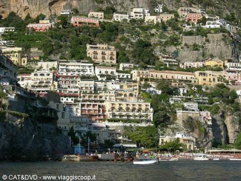 Colorful houses stacked on the Positano cliffside, boats in the foreground sea