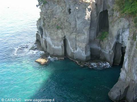 Rocky cliff with caves above turquoise water