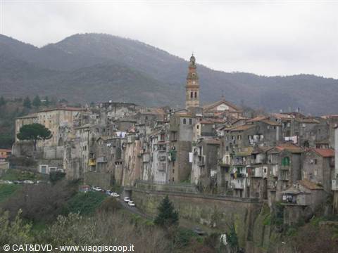 medieval hill town with stone houses and bell tower under cloudy mountains