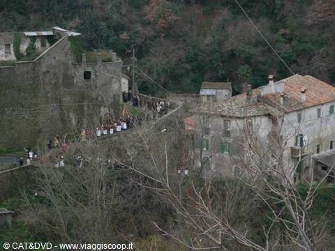 Procession of people in a line on an old stone bridge in the village