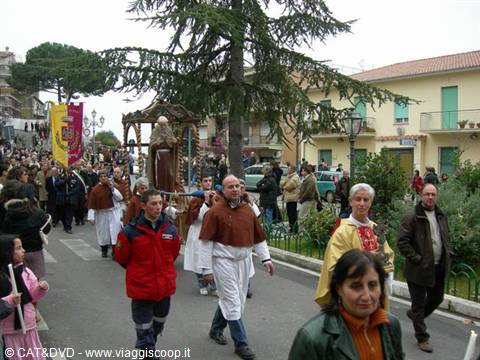 Religious procession with saint statue carried on shoulders through town streets