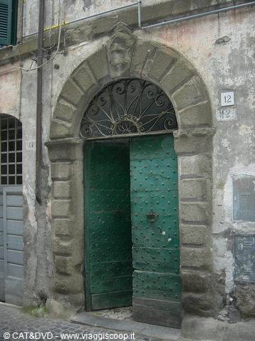 Green studded wooden doorway under grey stone arch, house number twelve