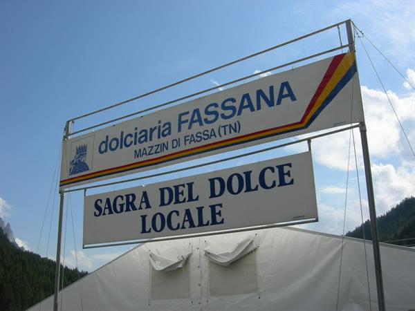 Fassana pastry shop signs and local dessert festival, Mazzin di Fassa, above a white tent