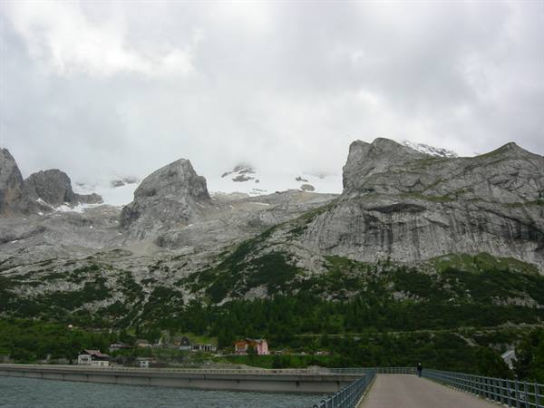 Fedaia dam below Marmolada, rocky peaks and snow under clouds