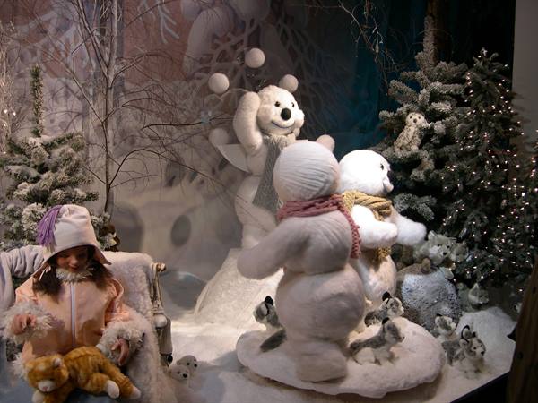 Christmas window display with plush snowmen among lit fir trees