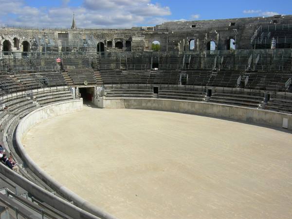 The Roman amphitheater of Arles, stone tiers and sandy arena under sun