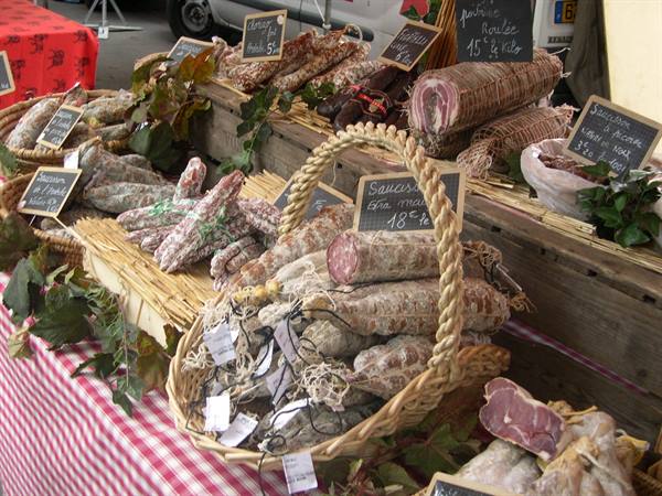 Wicker baskets of salami and sausages at a farm market, chalkboard prices
