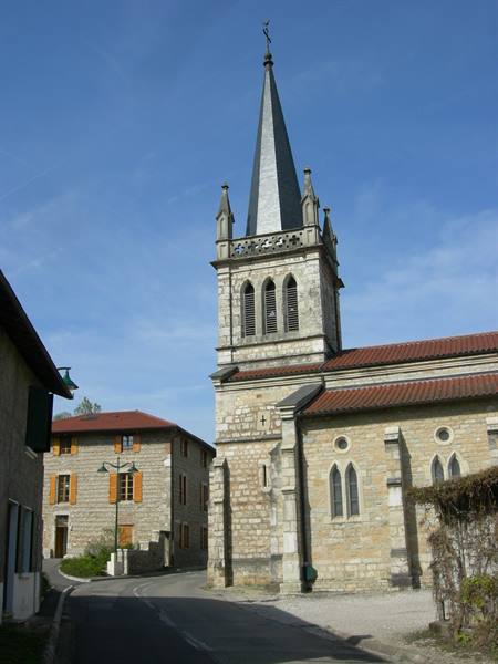 Stone bell tower with grey spire above stone houses in the village