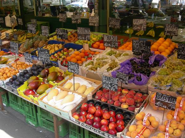 Fruit stall at German market with chalk signs, oranges, peaches and grapes in crates