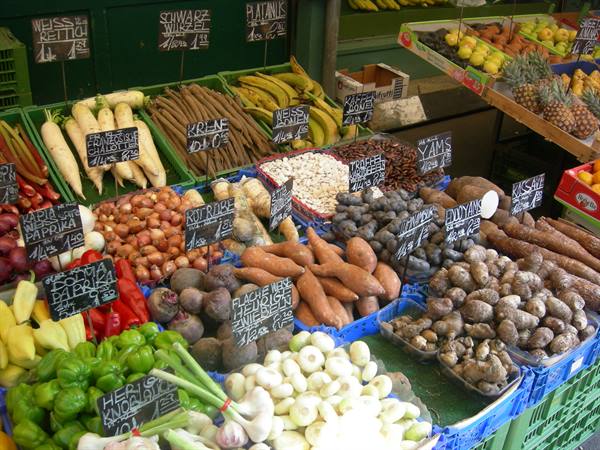 Market stall displaying fresh vegetables and root crops with price signs