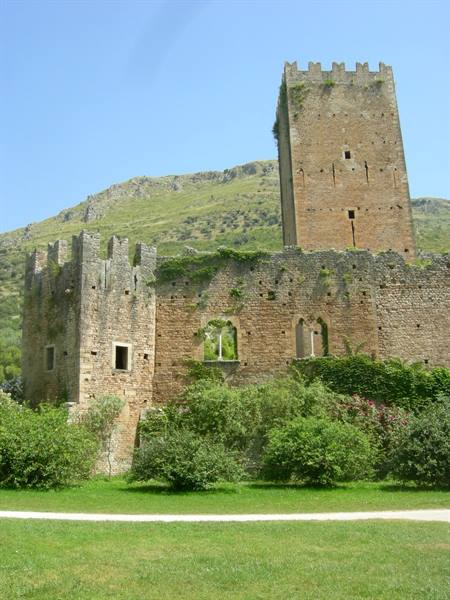 Crenellated stone tower and castle walls with green lawn below